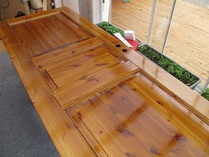 Käsittelemättömänä ostetut  väliovet käsittelyssä. Tässä Viherhuoneen varaston ovi terva - pellavaöljykylvyssä.