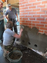 Tilalle hirsitaloa puolisonsa kanssa rakentava Sari Kuusisto kokeilee savirappausta muurarimestari Pauli Leinosen ohjauksessa, http://www.takkamestari.fi/.